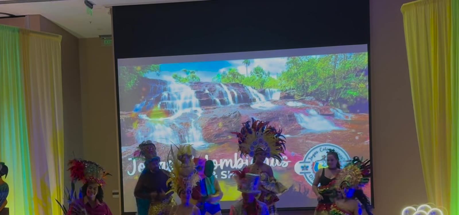 Escenario de Joyas Colombianas con cortinas de colores y bailarines frente a la pantalla del show